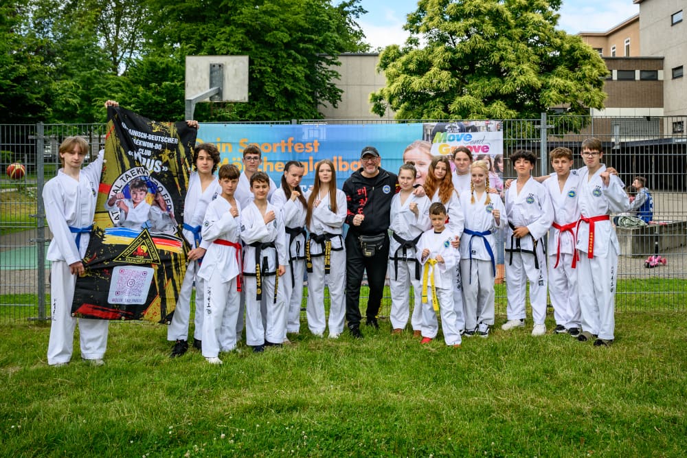 Karategruppe mit Trainer präsentiert sich beim Sportfest Move & Groove im Hugo Junkers Park.