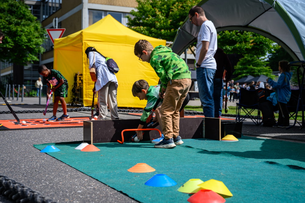 Kinder probieren Hockey an einer Mitmachstation beim Sportfest Move & Groove im Hugo Junkers Park aus.