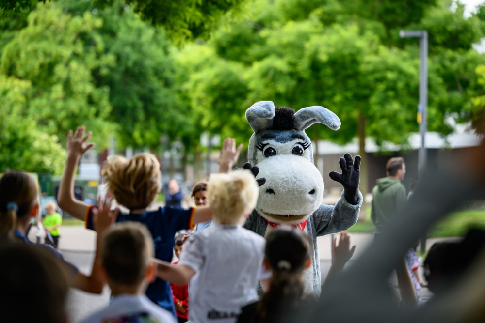 Das Maskottchen Goldi der Stadtsparkasse begrüßt Kinder beim Sportfest Move & Groove im Hugo Junkers Park.