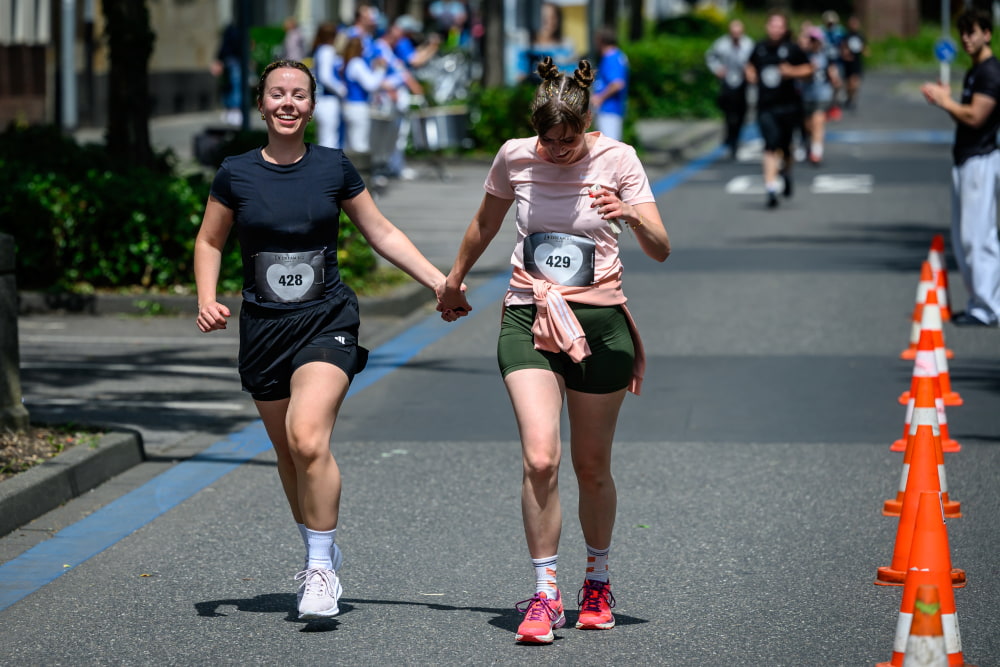 Zwei Teilnehmerinnen laufen Hand in Hand auf der Laufstrecke beim Sportfest Move & Groove.