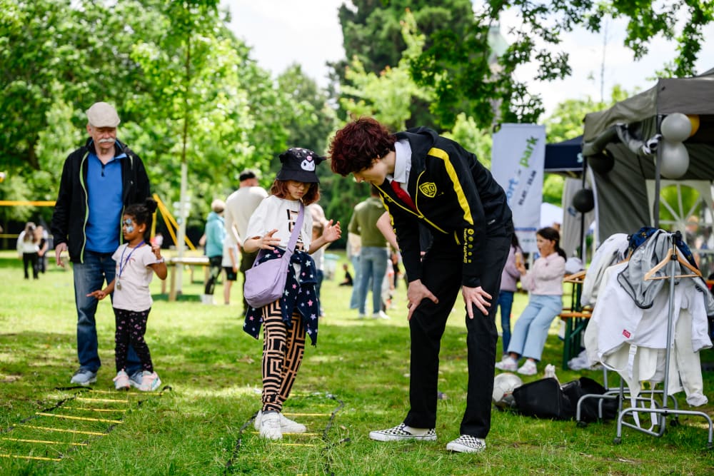 Ein Kind absolviert eine Koordinationsübung mit einer Leiter unter Anleitung beim Sportfest Move & Groove.