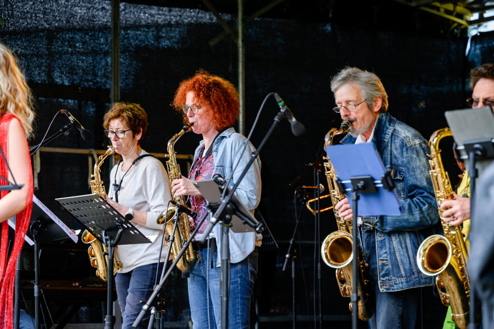 Mitglieder einer Liveband spielen Saxofon beim Bühnenprogramm des Sportfests Move & Groove.